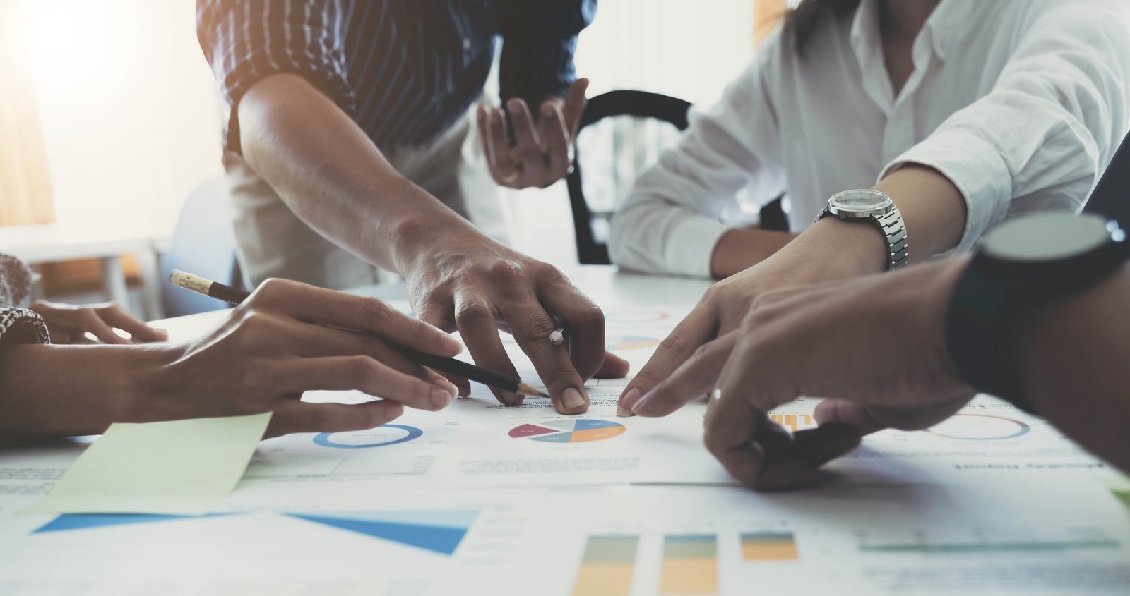 Tim konsultan dan klien menganalisis data bisnis bersama di atas meja kerja